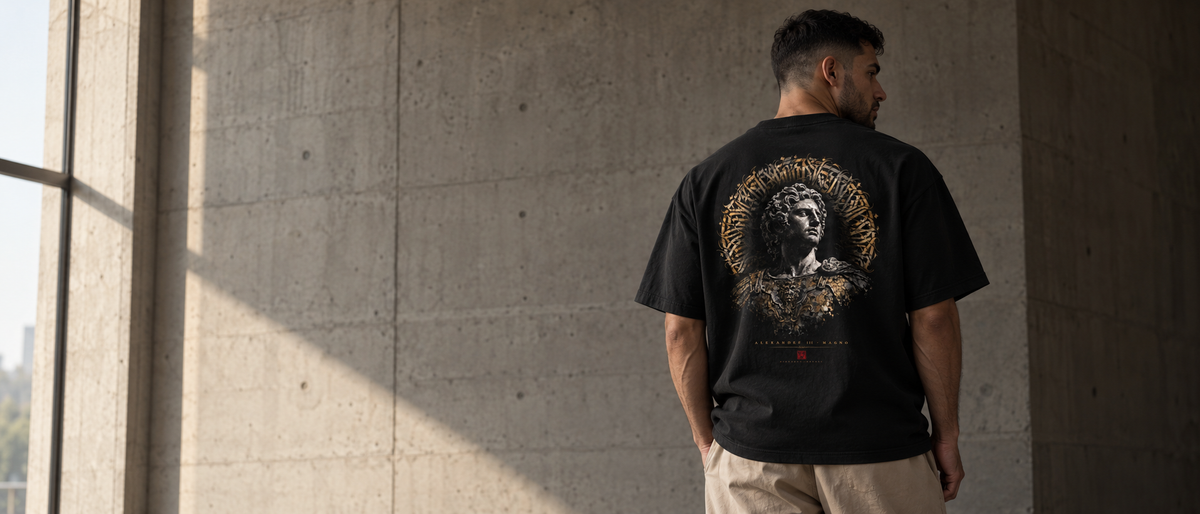Homem vestindo a camiseta oversized Alexandre Magno da coleção MOTUS, de costas, em parede de concreto